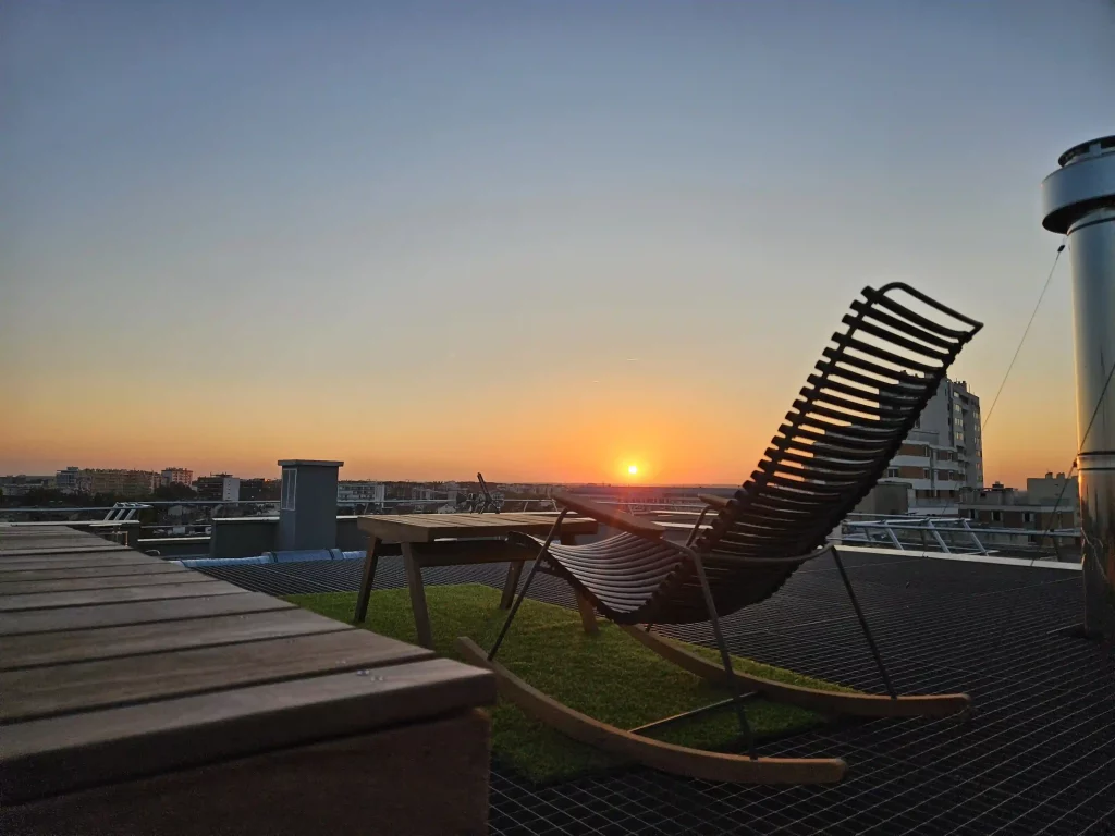 Terrasse moderne sur le toit à Toulouse avec chaise longue devant un coucher de soleil, conçu par un paysagiste local.