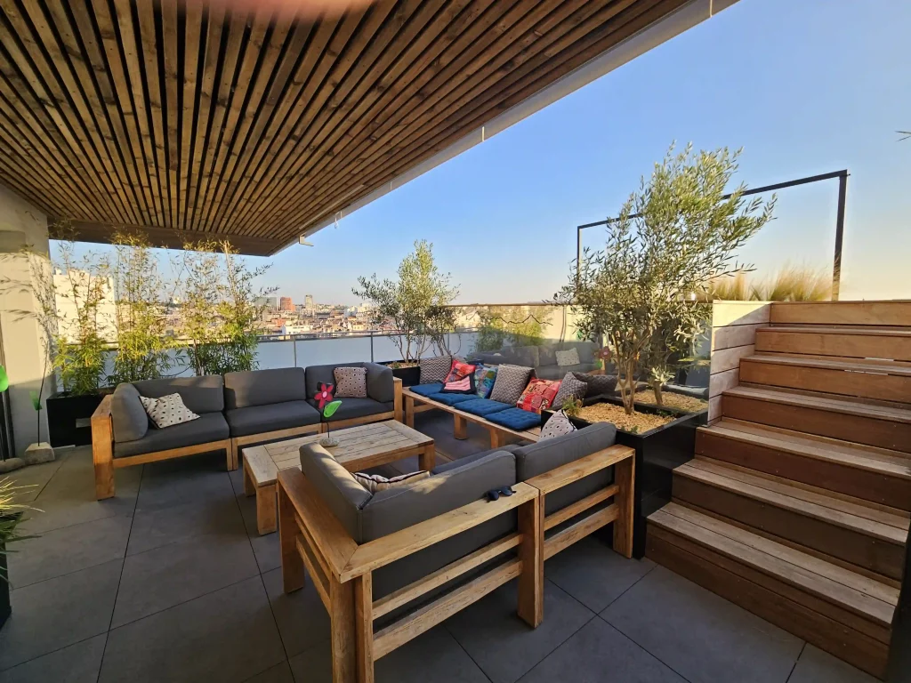 Terrasse sur les toits à Toulouse aménagée par un jardinier paysagiste, avec canapés confortables et plantes vertes.